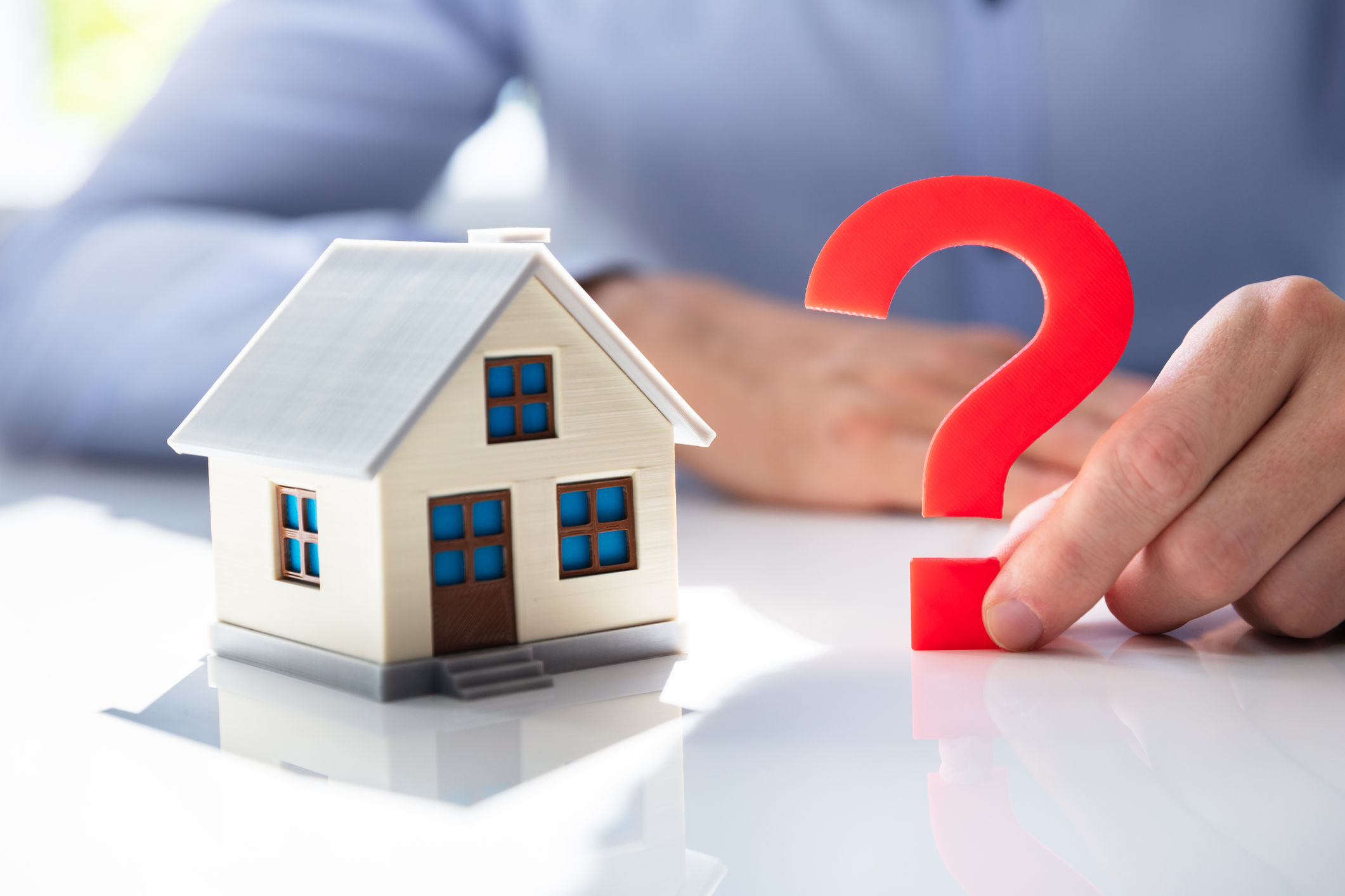 Man Holding Question Mark Next To House Model